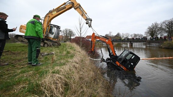 ein Bagger zieht einen weiteren Bagger aus einem Kanal in Greetsiel (Landkreis Aurich). © picture-allaince/dpa Foto: Lars klemmer