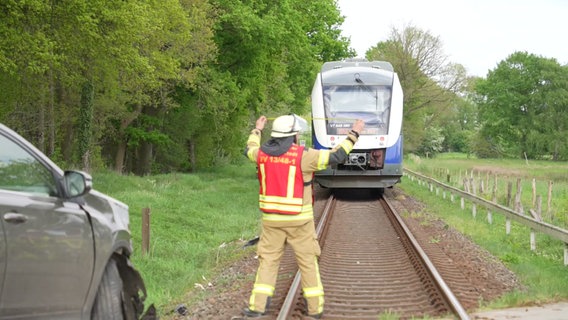 Ein Feuerwehrmann steht nach einem Unfall an einem unbeschrankten Bahnübergang bei Goldenstedt (Landkreis Vechta) auf den Gleisen. © Nord-West-Media TV 