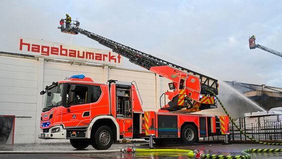 Ein Feuerwehrmann löscht aus der Drehleiter einen Brand in einem Baumarkt in Varel (Landkreis Friesland). © dpa-Bildfunk Foto: Lars Penning/dpa