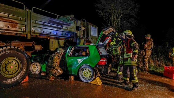Feuerwehrleute und Soldaten an einem grünen Kleinwagen, der halb einem großen Bundeswehrfahrzeug steht Feuerwehrleute und Soldaten an einem grünen Kleinwagen, der halb einem großen Bundeswehrfahrzeug steht © Polizeiinspektion Wilhelmshaven/Friesland
