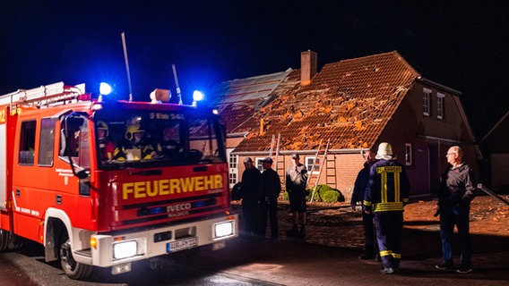 Ein Einsatzfahrzeug der Feuerwehr steht vor einem Haus, das bei einem Sturm am Dach beschädigt worden ist. © dpa-Bildfunk Foto: Mohssen Assanimoghaddam
