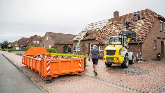 Helfer reparieren ein bei einem Unwetter beschädigtes Hausdach. © dpa-Bildfunk Foto: Mohssen Assanimoghaddam