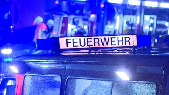 Feuerwehr-Fahrzeug bei Nacht; im Hintergrund Feuerwehrleute © NonstopNews 