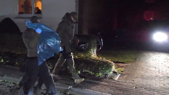 Polizeibeamte tragen bei Dunkelheit Gegenstände in blauen Plastiktüten. © dpa-TNN/dpa Foto: Jörn Hünecke