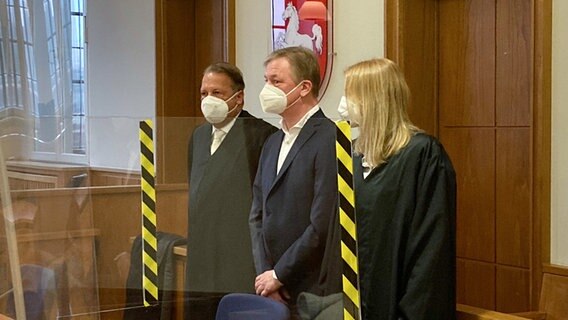 Der frühere Vorstandsvorsitzende des Energieversorgers EWE, Matthias Brückmann (M), steht als Angeklagter in einem Sitzungssaal des Landgerichts Oldenburg. Neben ihm stehen seine Verteidiger Marike Schupeta und Alfred Dierlamm. © dpa Foto: Friedemann Kohler