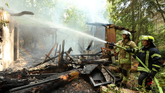 Einsatzkräfte der Feuerwehr löschen eine brennende Hütte in einem Waldgebiet. © Nord-West-Media TV 