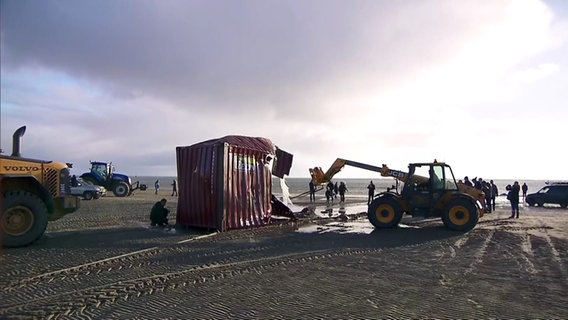 Am Strand liegende Container werden mit schwerem Gerät geborgen. © NDR Foto: André Steffens