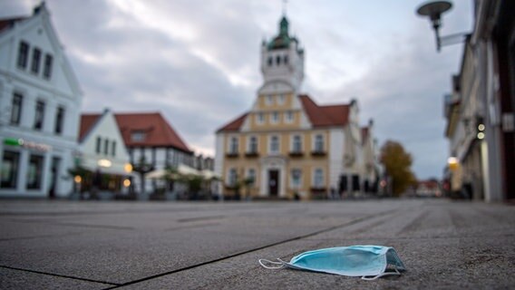 Eine Mund-Nasen-Schutz liegt auf dem Boden vor dem Rathaus. © dpa - Bildfunk Foto: Sina Schuldt