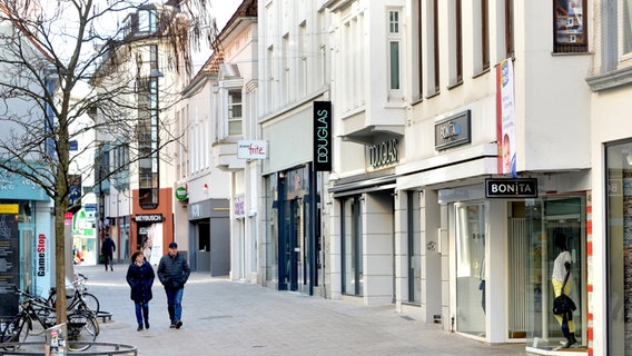 Zwei Personen gehen durch die sonst menschenleere Innenstadt Oldenburgs. Die Geschäfte sind geschlossen. © picture alliance Foto: Hauke-Christian Dittrich