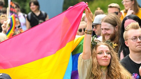 Eine Teilnehmerin des Christopher Street Day hält eine Fahne hoch. © Mohssen Assanimoghaddam/dpa Foto: Mohssen Assanimoghaddam