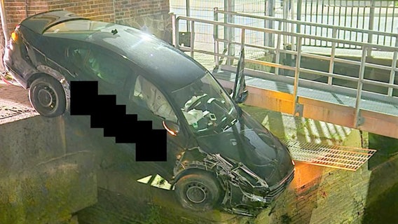 Ein Auto hängt über einem Hafenbecken in Cuxhaven. © Polizeiinspektion Cuxhaven 