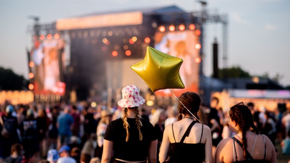 Festivalbesucherinnen verfolgen in der Abendsonne ein Konzert auf dem Deichbrand Festival. © picture alliance / dpa | Hauke-Christian Dittrich Foto: Hauke-Christian Dittrich