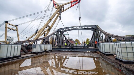 Eine Pfütze auf der Deichbrücke. Im Hintergrund ein Schwimmkran. © dpa-Bildfunk Foto: Sina Schuldt