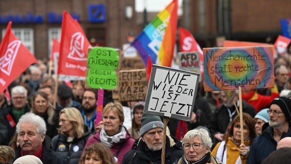 Teilnehmer einer Demonstration, zu der das «Leeraner Bündnis Gegen Rechts» aufgerufen hat, haben sich auf dem Denkmalsplatz versammelt, auf einem Schild steht "Nie wieder ist jetzt". © Lars Penning/dpa Foto: Lars Penning