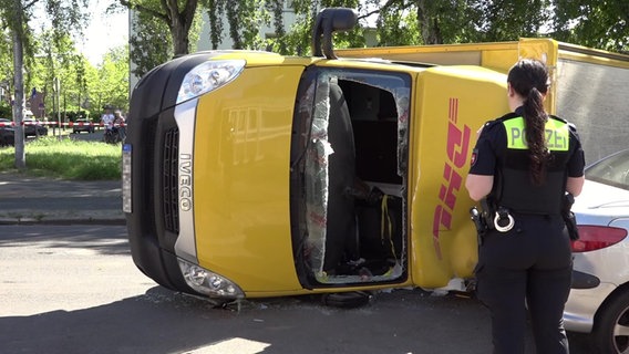 Eine Polizistin steht vor einem umgekippten DHL-Lieferwagen nach einem Unfall. © Nord-West-Media TV 