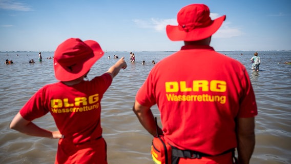 Mitglieder der DLRG (Deutsche Lebens-Rettungs-Gesellschaft) stehen am Strand von Dangast. © dpa Foto: Sina Schuldt