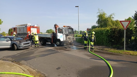 Feuerwehrleute löschen einen Kleinlaster nach einem Unfall mit einem Stromkasten. © Nord-West-Media TV 