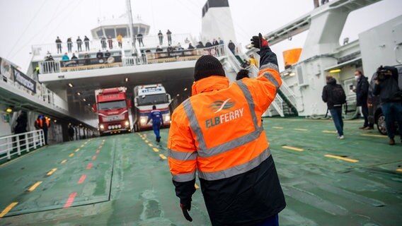 Ein Mensch weist Fahrzeuge auf einer Fähre ein. © picture alliance/dpa Foto: Sina Schuldt