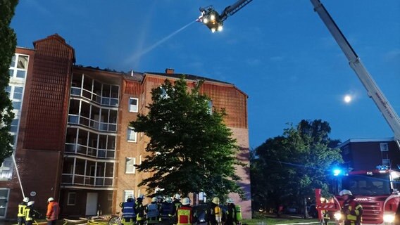 Einsatzkräfte der Feuerwehr löschen einen Dachstuhlbrand von einer Drehleiter aus. © Kreisfeuerwehrverband Aurich e.V. 