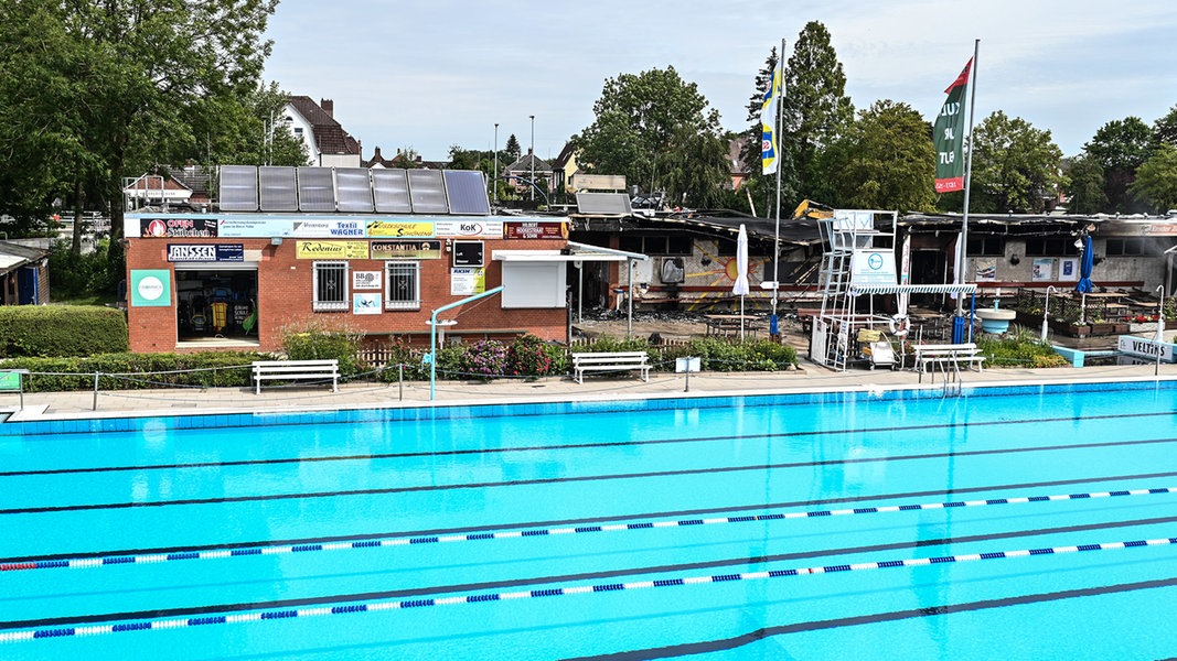 Blick Schwimmbecken auf ein ausgebranntes Gebäude des Van-Ameren-Freibads. 