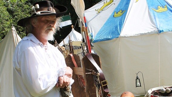 Ein Mann mit Hut steht vor Pfeilen aus der Epoche des Dreißigjährigen Krieges. © Landesmuseum Emden 