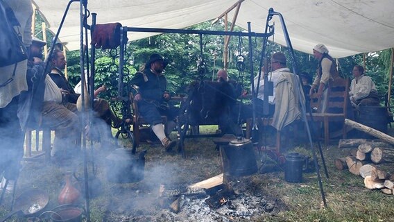 In einem Zelt sitzen Personen an einem Feuer. © dpa - Bildfunk Foto: Carmen Jaspersen