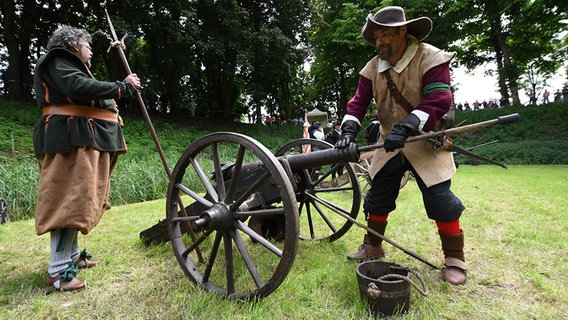 Ein historisch gekleideter Mann stopft eine Kugel in eine Kanone. © dpa - Bildfunk Foto: Carmen Jaspersen