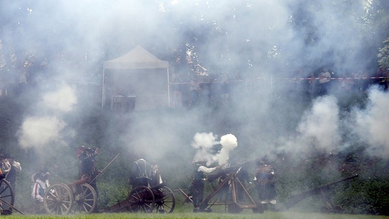 Auf einer Wiese stehen Kanonen aus denen Rauch und Qualm aufsteigt. © dpa - Bildfunk Foto: Carmen Jaspersen