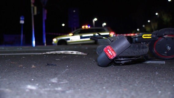 Ein E-Scooter liegt nach einem Unfall auf einer Kreuzung, im Hintergrund ein Polizeiwagen. © NonstopNews 