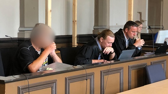 Ein Angeklagter sitzt mit seinen Verteidigern vor Gericht. © NDR Foto: Maren Momsen