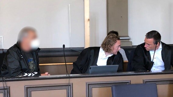 Der Anklagte (links) in einem Mordprozess mit seinen Verteidigern im Gerichtssaal. © NDR Foto: Maren Momsen