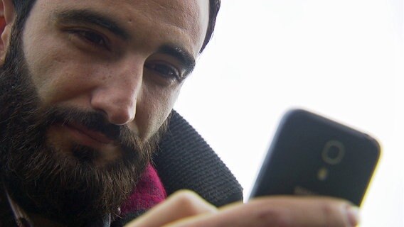 Basel Taifour schaut auf das Display seines Handys. © NDR Foto: Silke Rudolph