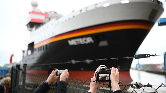 Menschen fotografieren in Papenburg das neue deutsche Forschungsschiff "Meteor IV", das die Bauhalle verlassen hat. © dpa-Bildfunk Foto: Lars Penning