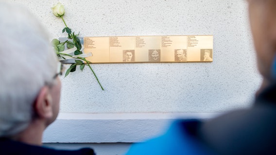 Besucher betrachten eine Tafel mit den Namen der ehemaligen jüdischen Familien Gerson und Cohen, die am ehemaligen Wohnhaus in Osternburg angebracht ist. © picture alliance/Hauke-Christian Dittrich Foto: Hauke-Christian Dittrich