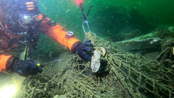 Ein Taucher schneidet ein Fischernetz am Grund der Nordsee frei. © Ghost Diving Germany 