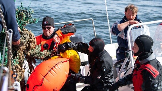 Die Tauchergruppe der Ghost Diving Germany übergibt ein gefundenes Geisternetz an die Besatzung des Kutters. © picture alliance/dpa | Melissa Erichsen Foto: Melissa Erichsen