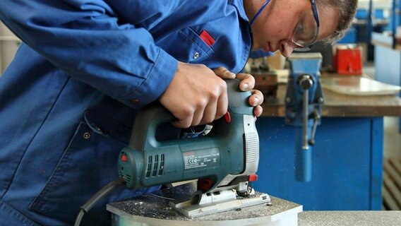 Ein Mensch mit Schutzbrille benutzt eine elektrisch betriebene Säge. Ein Mensch mit Schutzbrille benutzt eine elektrisch betriebene Säge. © Handwerkskammer Oldenburg Foto: Sascha Schneider