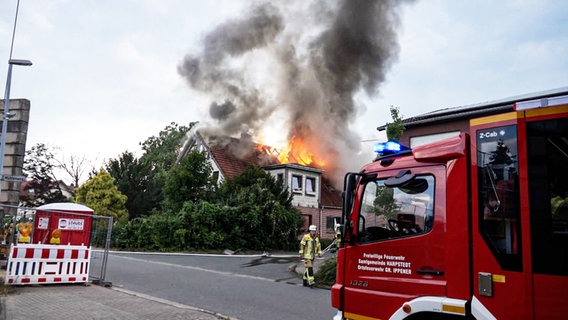 Hohe Flammen schlagen aus dem Dach eines Einfamilienhauses. Davor ein Feuerwehrwagen. © TeleNewsNetwork Foto: TeleNewsNetwork