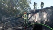 Feuerwehrleute löschen einen abgebrannten Schuppen in HAtten. Schuppen brennt in Hatten © Nord-West-Media TV 