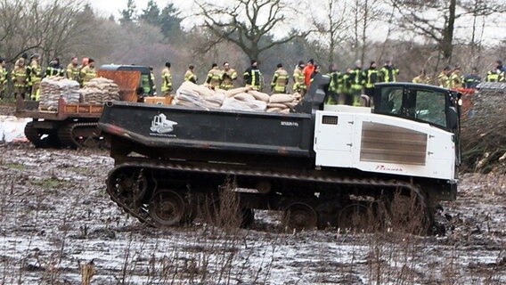 Einsatzkräfte mit schwerem Gerät (Kettenfahrzeugen) sichern einen Deich nahe eines Bahndamms an der Hunte im Ortsteil Sandkrug. © Uwe Arndt/Nord-West-Media TV/dpa Foto: Uwe Arndt