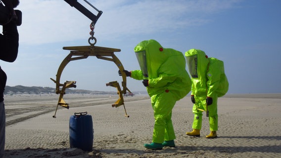 Zwei Personen in hellgrünen Schutzanzügen bei einer Übung des Havariekommandos am Strand von Wangerooge © NDR Foto: Matthias Schuch