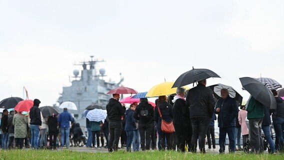 Fregatte "Hessen" läuft in Wilhelmshaven ein. Besucher mit Regenschirmen erwarten das Marineschiff. © dpa-Bildfunk Foto: Lars Penning