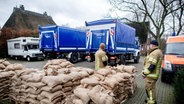 Einsatzkräfte der Feuerwehr und des Technischen Hilfswerks (THW) bereiten auf einem Parkplatz zahlreiche Sandsäcke zur Ausgabe an die Anwohner im Bereich der Hunte am Achterdiek vor. © Hauke-Christian Dittrich/dpa Foto: Hauke-Christian Dittrich