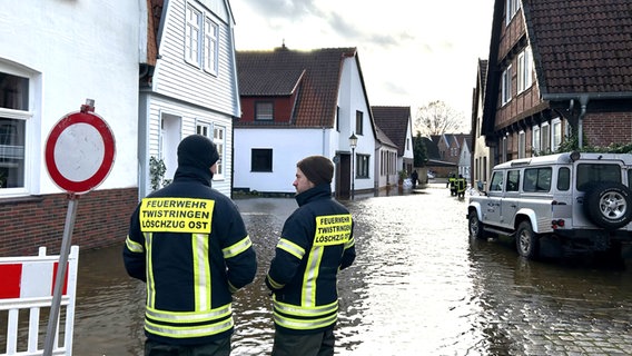 Einsatzkräfte der Feuerwehr stehen in einer überfluteten Straße in Verden. © NDR Foto: Anna Schlieter