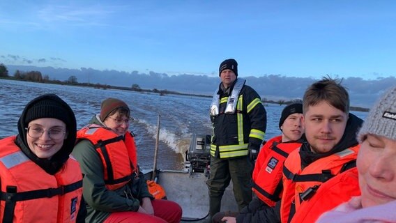 Einsatzkräfte der Feuerwehr transportieren Bewohner des Ortes Eissel mit einem Boot durch ein Hochwassergebiet. © NDR Foto: Mirco Seekamp