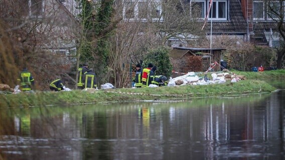 Feuerwehrleute sichern einen Deich an der Wörpe in Lilienthal mit Sandsäcken. © Focke Strangmann/dpa +++ dpa-Bildfunk +++ Foto: Focke Strangmann