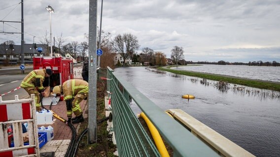 Feuerwehrleute pumpen Wasser aus der Wörpe in Lilienthal, um es zur Entlastung der Deiche auf die Wiesen eines nahe gelegenen Altarms zu leiten. © Focke Strangmann/dpa Foto: Focke Strangmann