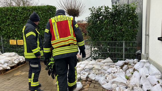 Einsatzkräfte der Feuerwehr tauschen nasse Sandsäcke in Verden aus. © NDR Foto: Maren Momsen