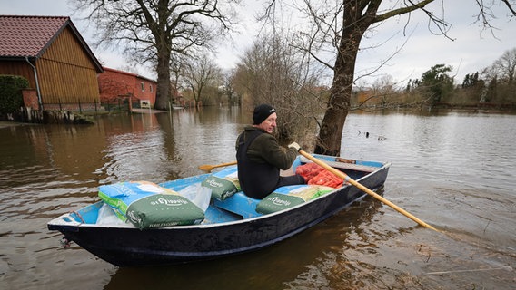 Stefan Ernst, Anwohner, bringt mit einem kleinen Ruderboot Futter für seine Tiere über eine überschwemmte Straße in Hagen-Grinden zu seinem Hof. © dpa-Bildfunk Foto: Christian Charisius