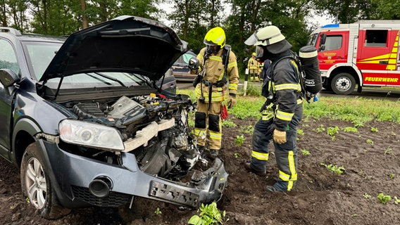Zwei Feuerwehrleute stehen vor einem kaputten Auto. © Feuerwehr Huntlosen Foto: Matthias Witthöft